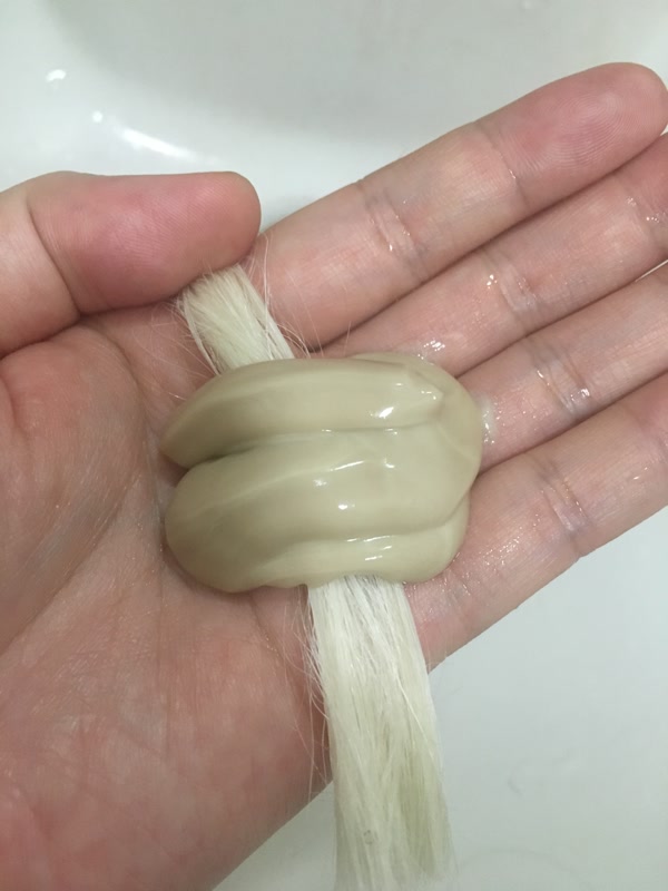 手のひらの毛束に、とろりとしたクリーム状の薬剤をのせた様子