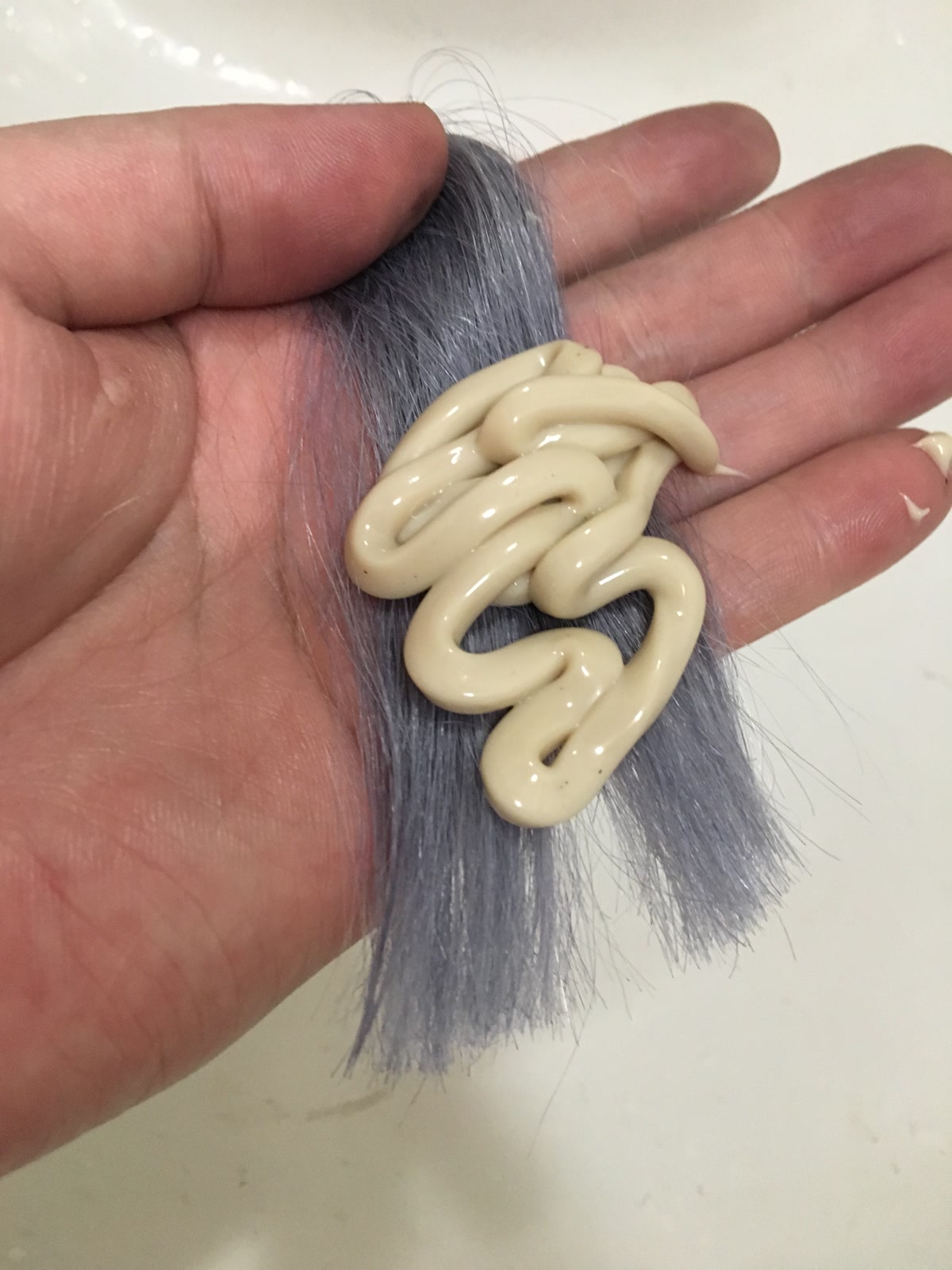 白髪の毛束にクリーム状の薬をたっぷりのせた手元の例